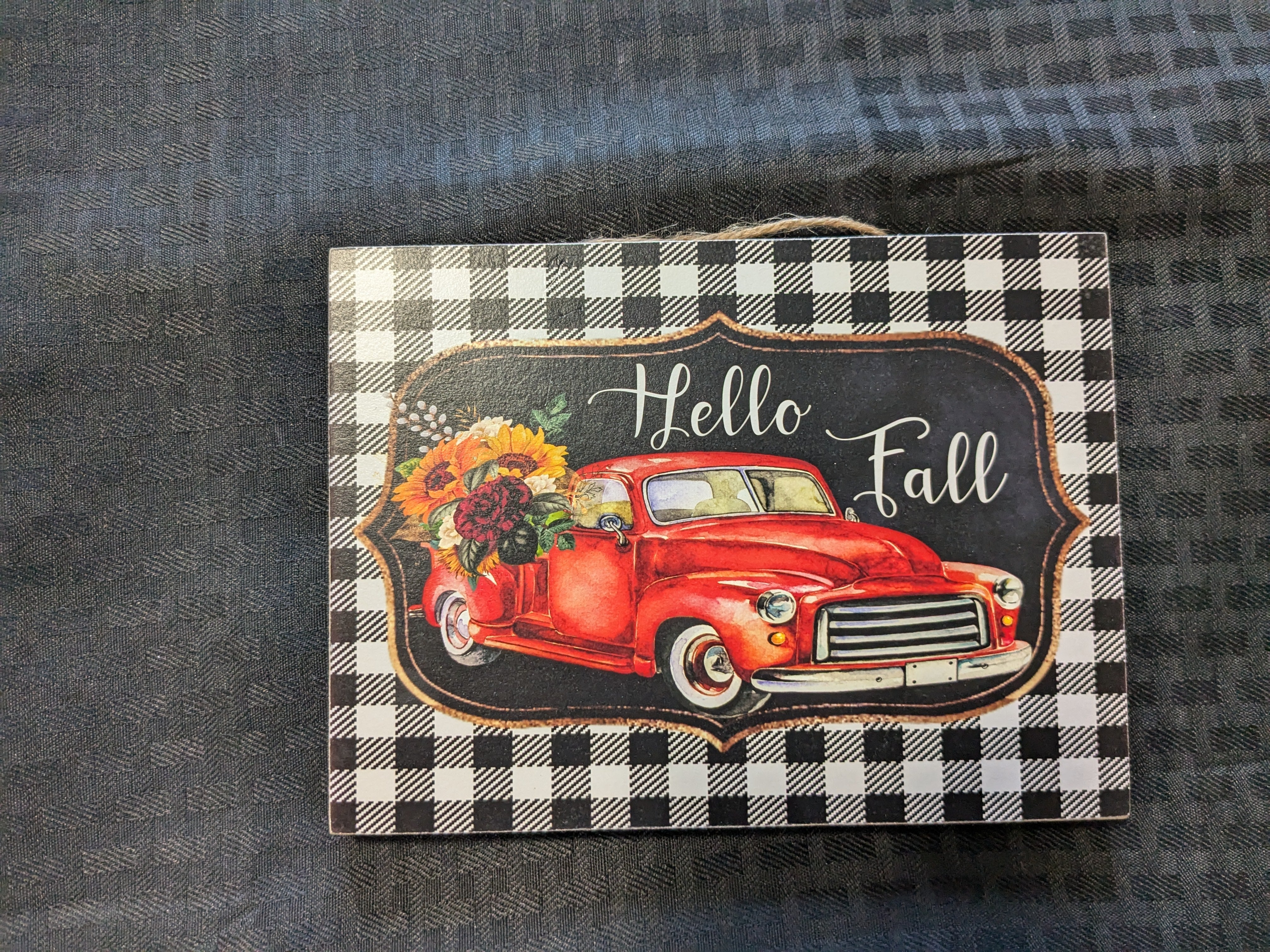 Hello Fall' truck hanging sign with gingham border – a charming readymade craft featuring a vintage truck design and adorned with white and orange pumpkin plaid blocks. Perfect for autumn decor, this decorative sign adds a warm, inviting touch to your home or entryway.